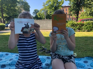 Zwei Kinder halten Bücher vors Gesicht